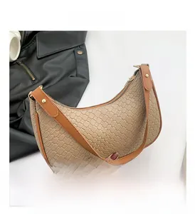 Detail shot of beige woven texture and brown leather strap on a crescent shoulder bag