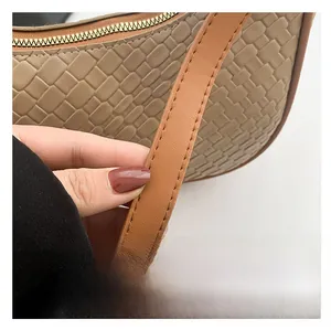 Detail of the woven texture and metal zipper on a khaki crossbody dumpling bag