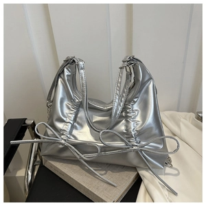 Detail of silver metallic pleated bag with large decorative bows and chain strap
