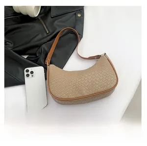Detail view of beige crossbody bag with crocodile texture next to a smartphone