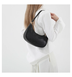 Detail of black woven hobo bag with moon shape and golden zipper on white outfit