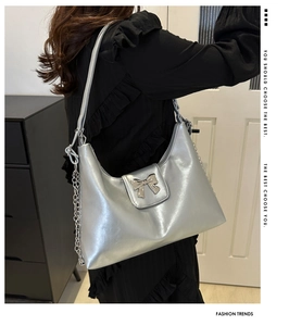 Detailed close-up of a silver bow buckle and glossy metallic texture on a tote bag