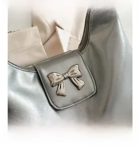 Silver metallic leather hobo bag featuring a polished metal bow buckle detail