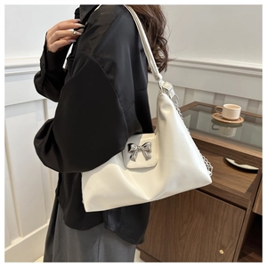 Close-up of white PU leather shoulder bag featuring a silver metal bow accent
