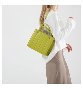 Detail of bright green quilted tote bag with golden chain strap and round handle