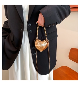 Detail of a golden heart-shaped evening bag with radial texture and metal bead handle