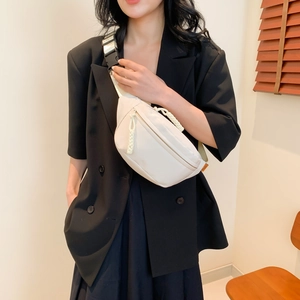 Marsupio minimalista in nylon beige con tracolla nera indossato da una modella