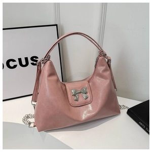 Detail of light pink patent leather tote bag with silver metal bow and chain strap