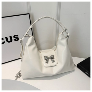 Close-up of white Hobo bag with large silver bow detail and metal chain strap