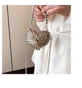 Détail du sac coeur en métal argenté avec texture plissée et chaîne en perles