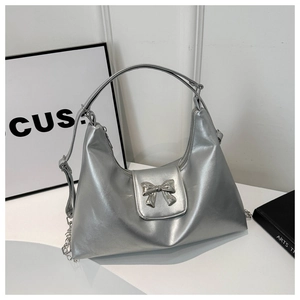 Close-up of metallic silver PU leather texture and decorative metal bow buckle on tote bag