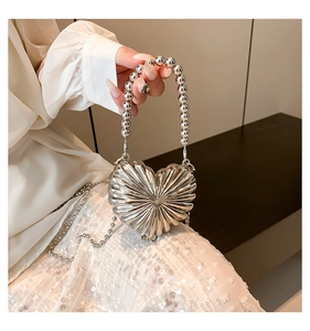 Detail of silver heart-shaped evening clutch with pleated texture and beaded chain