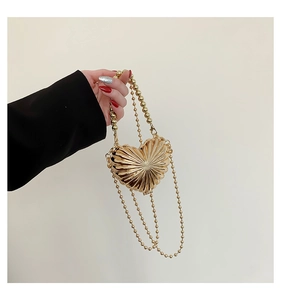 Detail of gold heart metal mini bag with radial texture and beaded chain strap