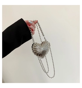 Detail of a mini heart-shaped silver metallic handbag with radial lines and bead chain