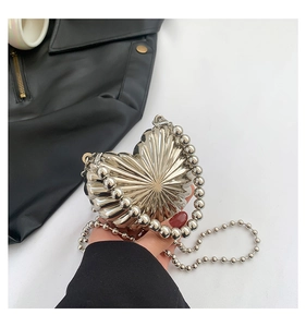 Détail du mini sac cœur argenté en métal texturé avec sa fine chaîne à billes chic