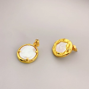 Vintage gold stud earrings with baroque pearl inlay and hammered texture on gray background