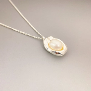 Minimalist silver necklace featuring organic metal charm with a white freshwater pearl