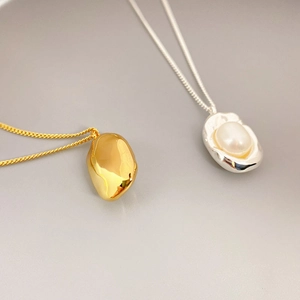 Minimalist bean-shaped metal necklace and freshwater pearl pendant in gold and silver