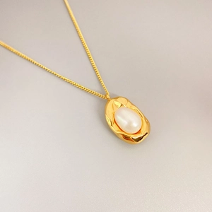 Detailed view of hammered gold pendant necklace featuring a round freshwater pearl