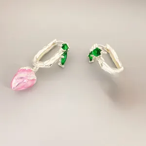 Macro detail of silver strawberry earrings with pink pearlescent enamel and green stone