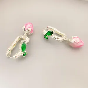 Detail of silver-plated flower bud earrings with pink enamel and green marquise gems