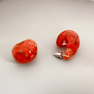 Macro detail of red resin flower earrings with silver needles and floral textures