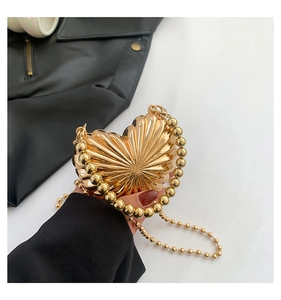 Detailed view of heart-shaped gold shell purse with metallic texture and chain