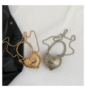 Detail of metallic heart-shaped mini bags with radial textures and pearl chain straps