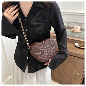 Macro shot of heart-shaped crossbody bag featuring white spider web print and gold chain