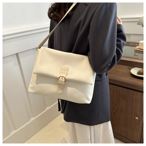 Sac à bandoulière beige minimaliste porté avec un blazer sombre pour un look de bureau