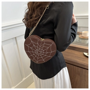 Detailed embroidery of a spider web and small heart on a brown heart-shaped purse