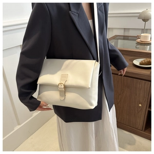 Gros plan d'un sac enveloppe en cuir blanc crème avec une boucle dorée vintage chic