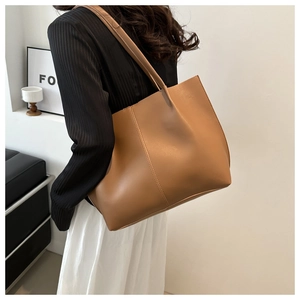 Lifestyle shot of large brown PU leather tote bag worn as a shoulder bag on a model