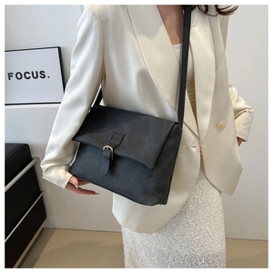 Détail d'un sac bandoulière noir mat avec boucle en métal vintage et rabat minimaliste