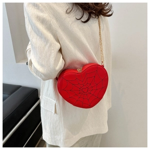 Close-up of heart-shaped crossbody bag with black spider web pattern and gold chain