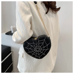 Black heart-shaped crossbody bag with white spider web embroidery and gold chain strap