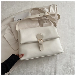 Détail du sac fourre-tout crème avec boucle dorée sur fond de blazer beige élégant
