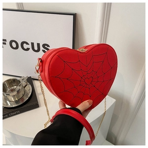 Close-up of red heart-shaped purse with black spider web embroidery and gold chain