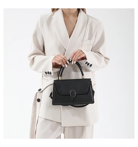 Dettaglio della borsa nera minimalista con pelle opaca e fibbia in metallo dorato ovale