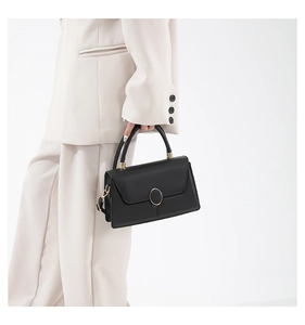 Dettaglio di un'elegante borsa in pelle nera opaca con chiusura dorata e manico