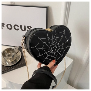 Close-up of heart-shaped handbag featuring white spider web stitching and gold chain