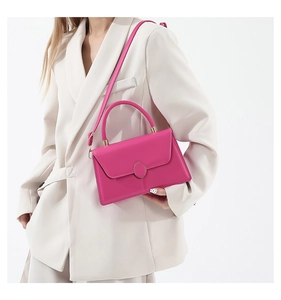 Dettaglio della borsa magenta con fibbia dorata indossata da modella in blazer bianco