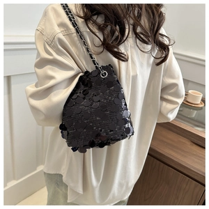 Detail of shimmering black sequins on bucket bag with silver metal chain strap