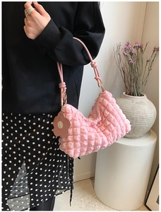Macro detail of pink bubble textured fabric and floral charm on a stylish bucket bag