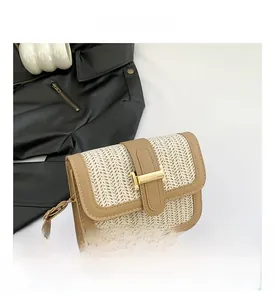 Gros plan sur la texture paille beige avec bordure en cuir camel et boucle dorée en H