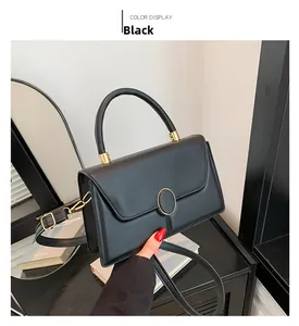 Dettaglio della piccola borsa quadrata in pelle nera con fibbia dorata tonda e manico