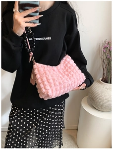 Pink popcorn texture bag with black bead handle and floral charm shown with outfit
