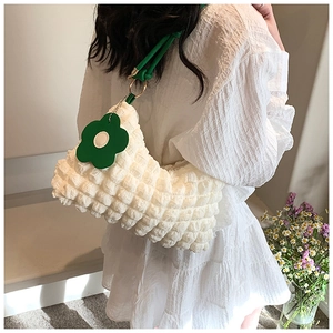 Detail of white popcorn texture bag with green handle and flower charm accessory