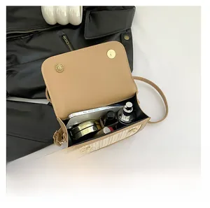 Détail de l'intérieur d'un sac en paille contrastée avec des produits de maquillage