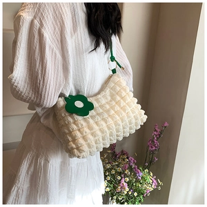 Detail of off-white bubble texture bag with a green flower charm and slim strap